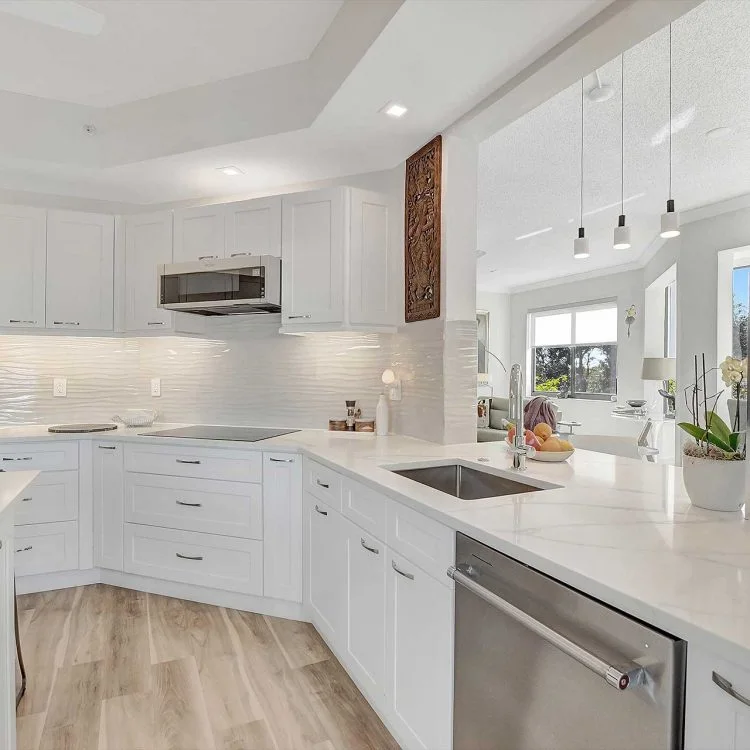 White cabinetry and pale counters around a kitchen sink