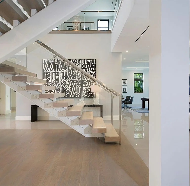 Floating staircase with pale wood treads and glass railing