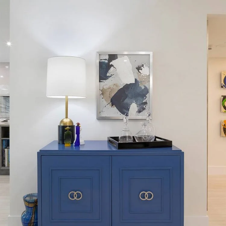 Blue entry cabinet with a lamp and abstract artwork