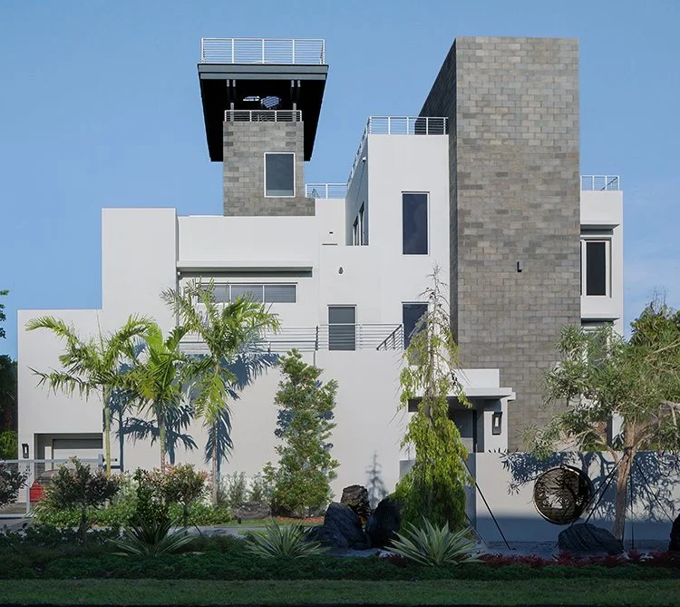 White facade with a tall stone-clad volume and tropical planting