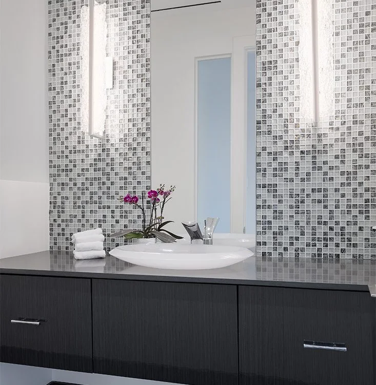 A jewel-like powder room with mosaic tile and a sculptural basin