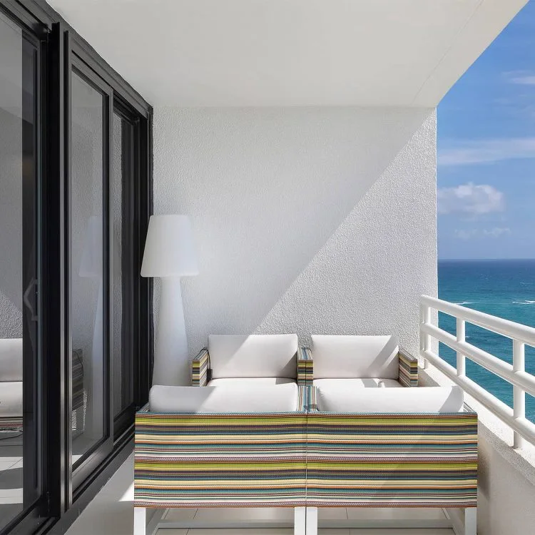An oceanfront terrace with a striped daybed and sweeping blue views
