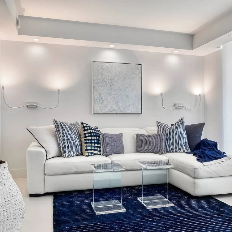 White sectional with blue cushions and a dark blue rug