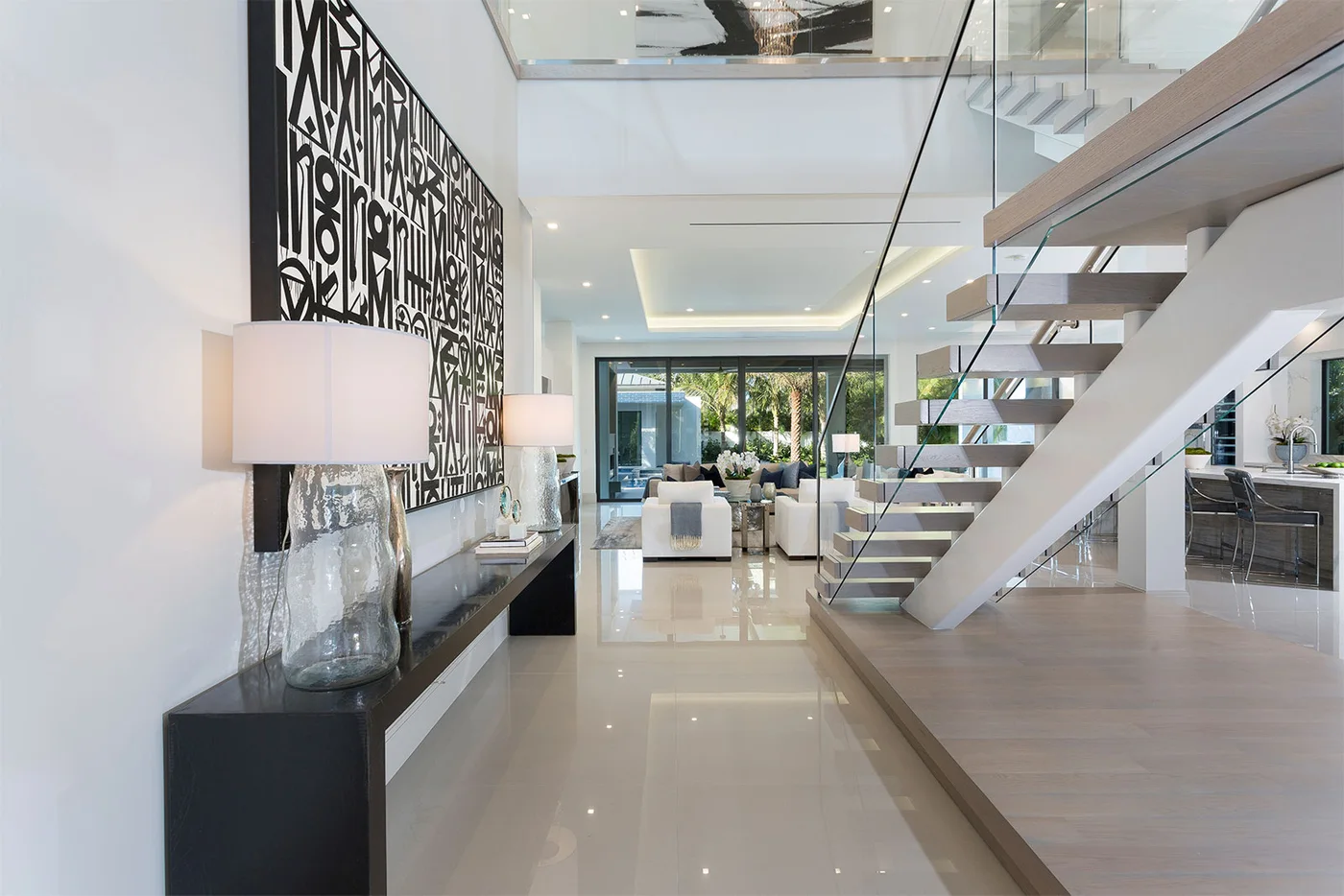 An open entry with a floating staircase and views through the home