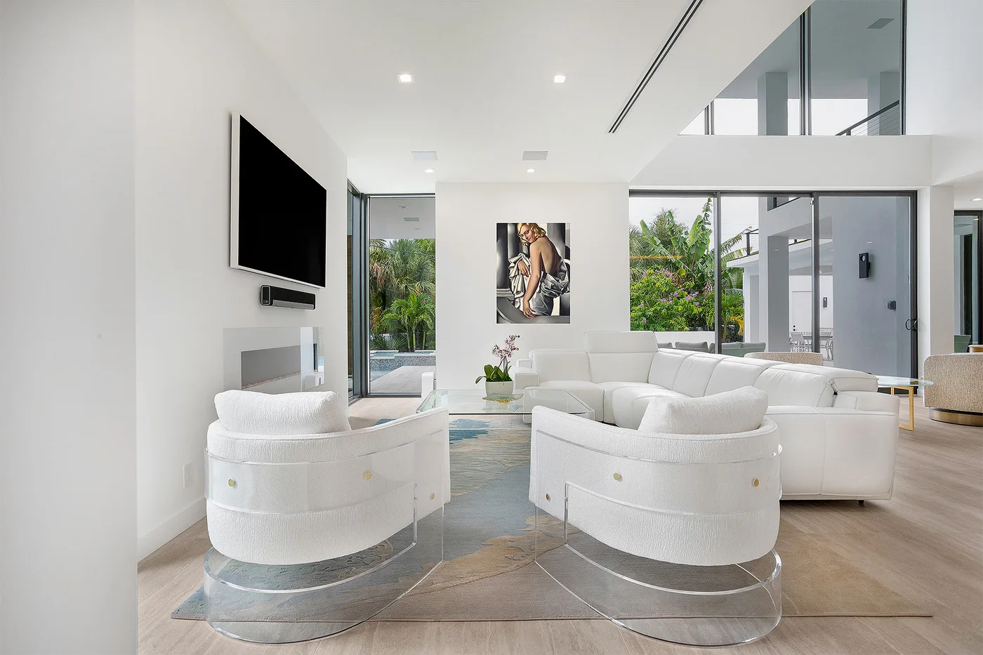 A contemporary living room with curved white chairs and garden views
