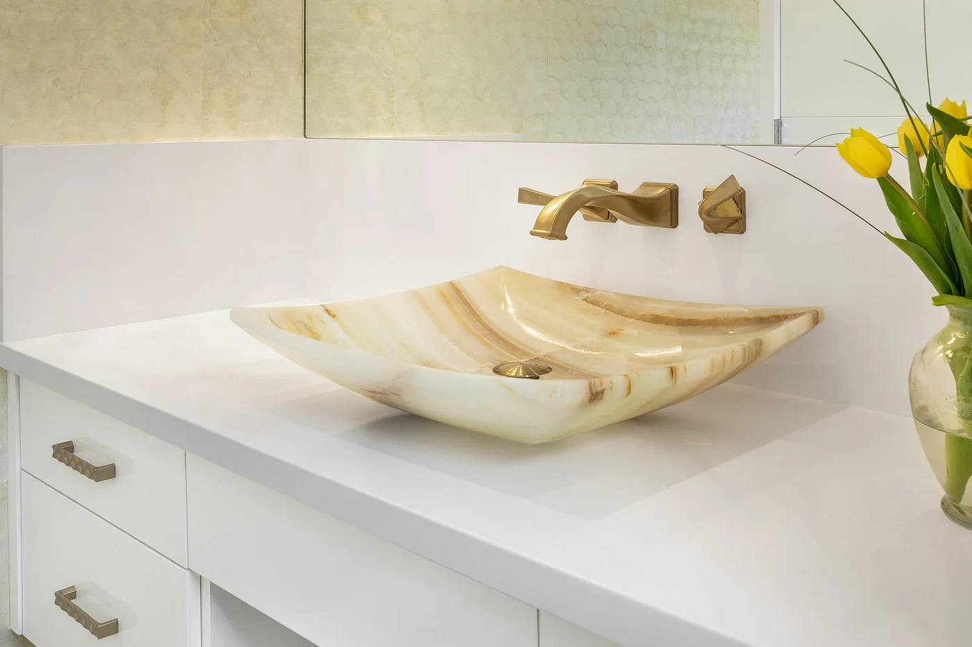 A sculptural stone basin with warm brass fittings
